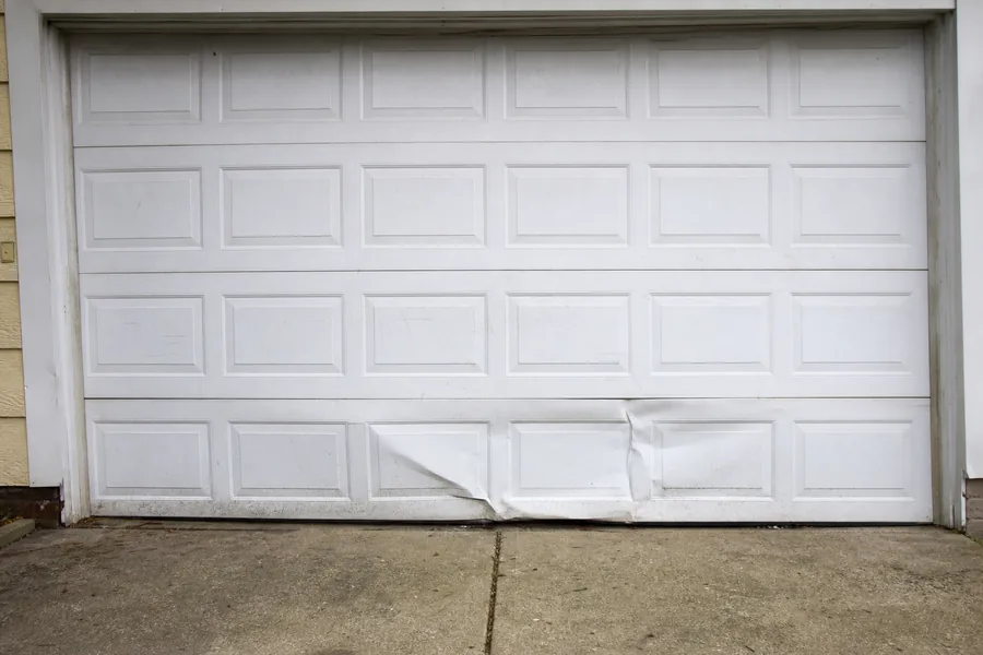 Dented panel sections on an older garage door in Rockford, IL