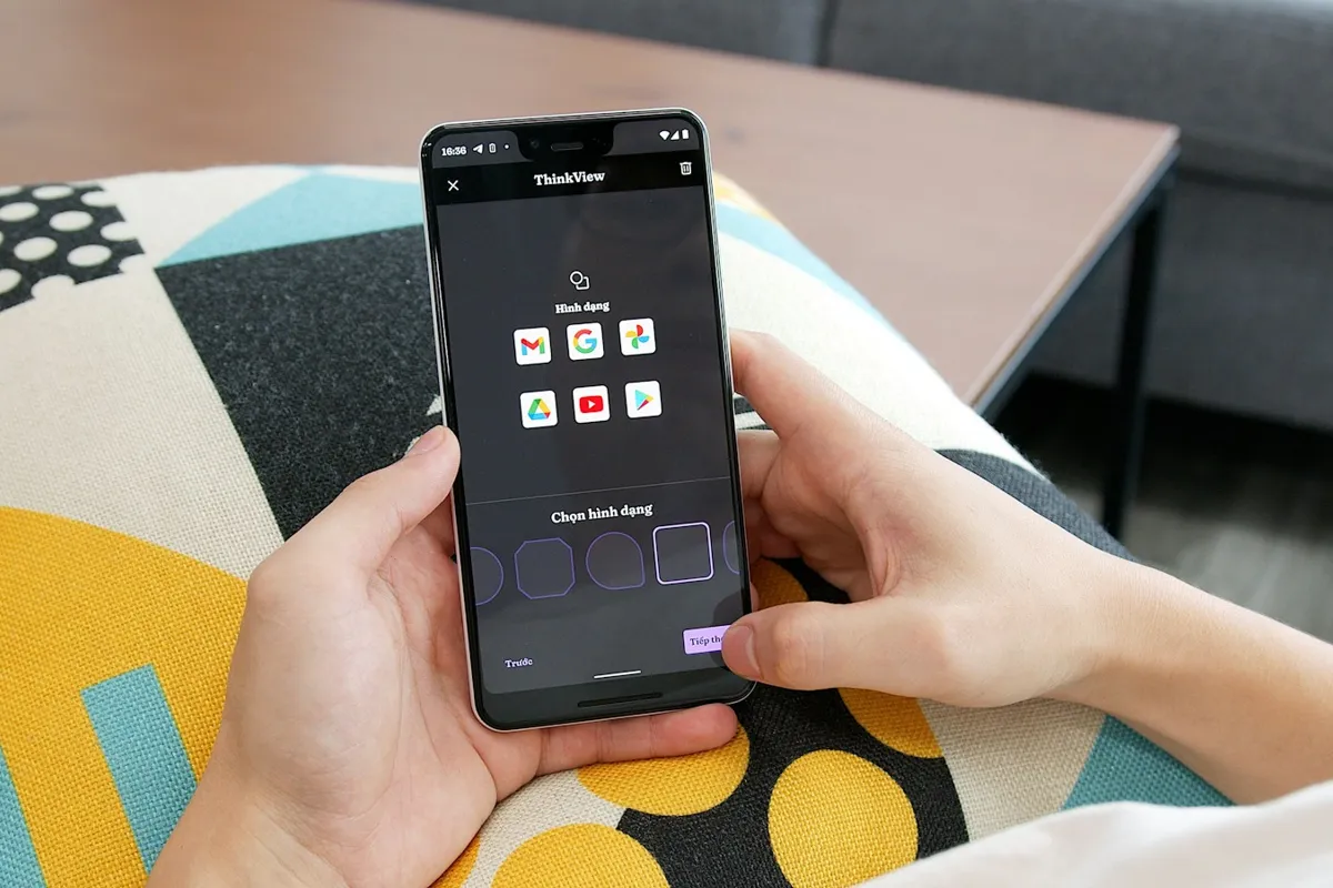 Hands holding a phone over a patterned cushion